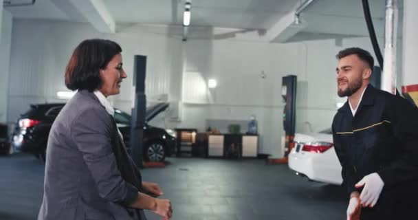 Jól néz ki menedzser nő öltönyben és a szerelő férfi vonzó megjelenés tánc a garázsban, miután befejezte a munkanap — Stock videók