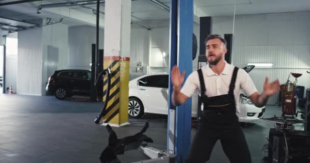 Good looking mechanic in a great mood after he finished the work start to dancing excited in front of the camera — Stock Video