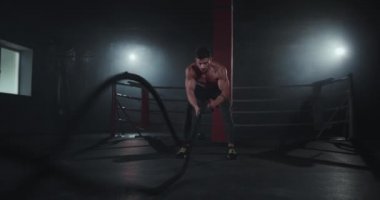 Karizmatik yüzlü, halatlarla egzersiz yapan beden eğitimi sınıfındaki atletik çocuk sıkı bir antrenman yapıyor. Yavaş hareketler