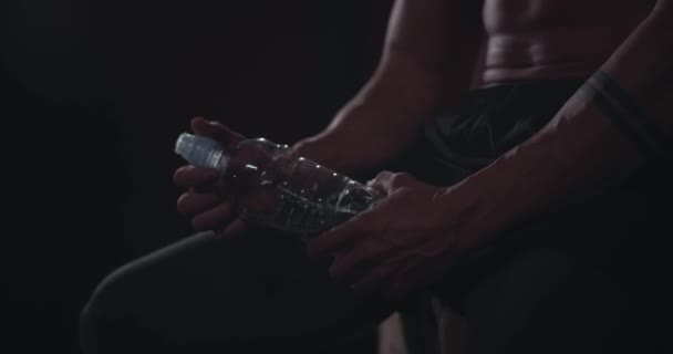 Detalhes abs corpo atlético cara segurando uma garrafa de água em uma aula de fitness cruz ele quer beber um pouco de água após seu treino intenso — Vídeo de Stock