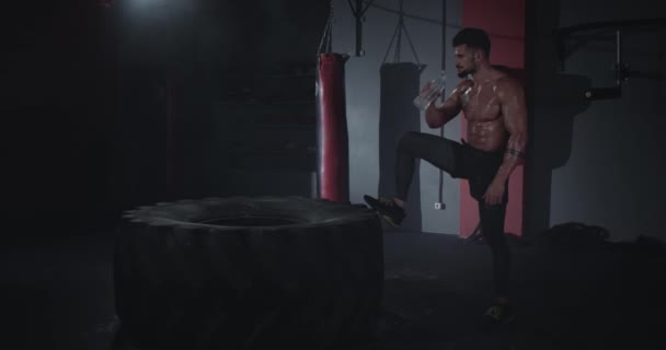 Hombre atlético de buen aspecto con un cuerpo dulce en una clase de fitness después de un entrenamiento muy duro, tiene mucha sed. — Vídeos de Stock