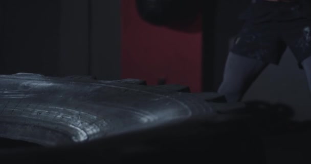 Tvrdá cvičení silný atletický muž cvičí pomocí hummer udeří přes velké pneumatiky velmi koncentrované plné síly těla — Stock video