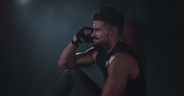 Hombre bastante sonriente con un cuerpo en forma después de su entrenamiento hablando por teléfono con alguien tiene una cara dulce después de un duro entrenamiento — Vídeos de Stock