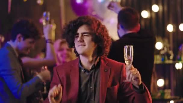 Tančící charismatický muž na večírku, zatímco drží sklenku šampaňského, si užívá večer zábavným pohybem a cítí se skvěle. Snímek na kameře Arri Cinema — Stock video