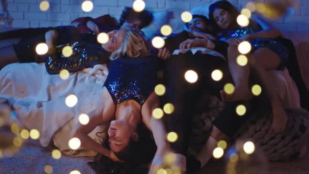 Группа молодых друзей засыпает после тяжелой домашней вечеринки они спят сладко на кровати все вместе в гламурных нарядах — стоковое видео