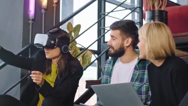 Grupo de estudiantes en la biblioteca después de la universidad disfrutando del tiempo juntos mientras hacen sus deberes usando las gafas de realidad virtual para explorar el mundo — Vídeos de Stock