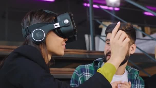 Groupe attrayant de jeunes amis sur la bibliothèque profitant de leur temps libre en utilisant les lunettes de réalité de dernière génération pour jouer à un jeu virtuel — Video