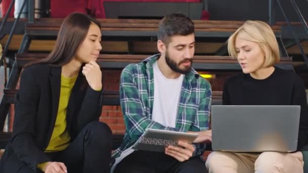 Usmívající se kancelářští pracovníci využívající virtuální brýle, užívající si čas v moderní kanceláři, zatímco sedí na schodech a užívají si čas v práci — Stock video