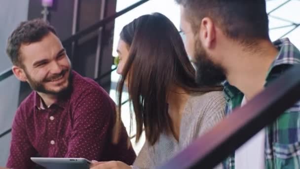 Primo piano tre studenti multietnici che fanno i compiti sulle scale del college analizzando il piano di lavoro mentre utilizzano un tablet — Video Stock