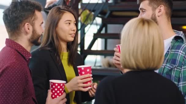 I ett modernt kontorshotell grupp av multietniska arbetare medan ha en kaffe paus har en vänlig konversation leende och njuta av kaffet — Stockvideo