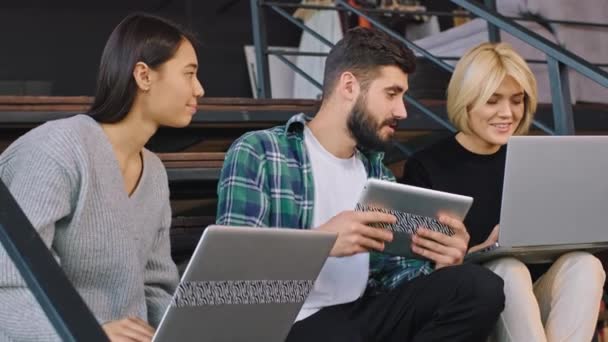 Modernas escaleras de oficina jóvenes trabajadores hacen el plan de trabajo utilizando el cuaderno y la tableta que disfrutan del trabajo — Vídeo de stock