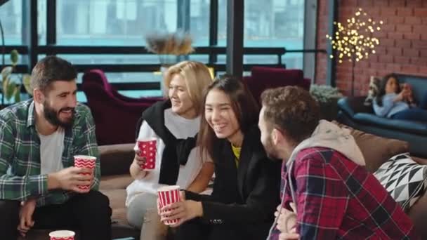 Na velké pohovce v moderní univerzitní knihovně multietnické dospělé studenty socializovat a užívat si čas při obědě — Stock video
