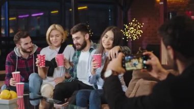 İki güzel bayan ve iki çekici erkek kanepede oturmuş hatıralar için fotoğraf çekerken mutlu hissediyorlar ve gülümsüyorlar.