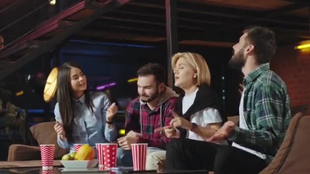 Смішно виглядає група молодих друзів, які проводять смішний час разом вони сидять на дивані вдома і почуваються розслабленими. 4k — стокове відео