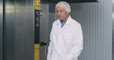 Yaşlı adam yemek mühendisi ve yardımcıları beyaz üniformalı fırın makinesi kadın yardımı için kontrol noktası oluşturuyorlar. Notları dijital tabletinden alın.