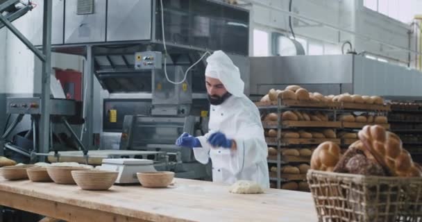 Fabrik-Lebensmittelbäckerei tanzender Bäcker in der gewerblichen Küche, der Musik aus drahtlosen Kopfhörern hört und die Zeit bei der Arbeit genießt. 4k — Stockvideo