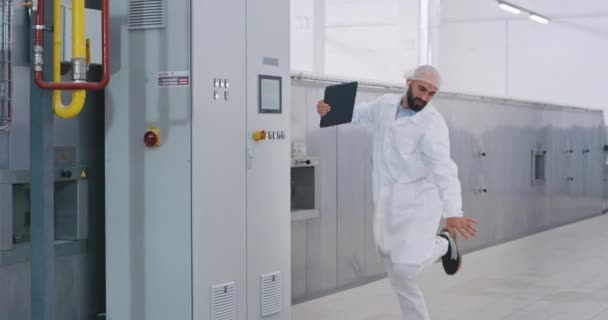 Bailando feliz ingeniero con auriculares inalámbricos comenzando el día de trabajo en un buen estado de ánimo después de llegar a la máquina industrial y empezar a comprobar — Vídeos de Stock