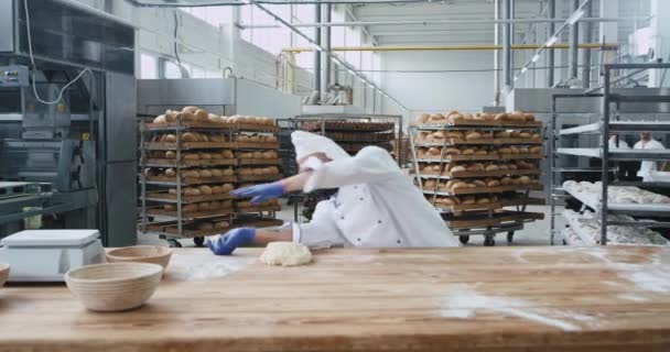 Aantrekkelijke en grappige volwassen bakker met baard in de commerciële keuken dansend terwijl hij muziek luistert met de draadloze hoofdtelefoon naast zijn werkplek — Stockvideo