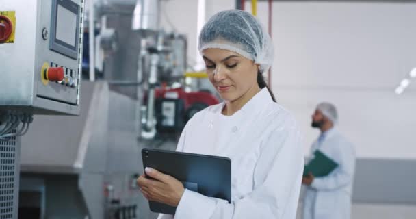 Retrato de uma mulher engenheira com um tablet de nova geração fazer algumas notas ao verificar a máquina industrial — Vídeo de Stock