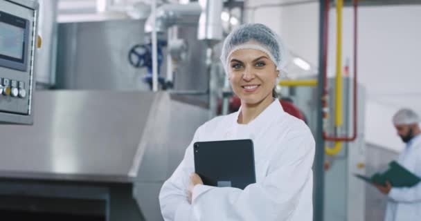 Портрет улыбается большая женщина инженер очень привлекательный холдинг электронный планшет стоя рядом с промышленной машины — стоковое видео