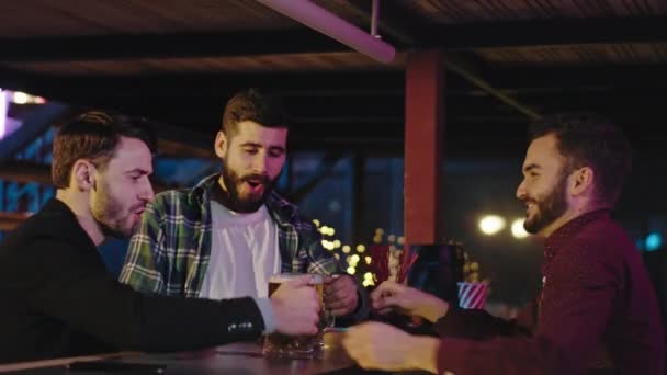 Charismatische blije vrienden na het werk kwamen naar de kroeg barman geven twee glas bier nemen ze twee mok koud bier en beginnen te drinken — Stockvideo