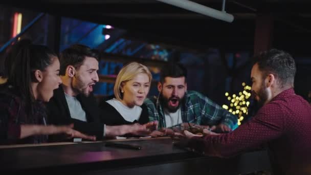 Grupp karismatiska attraktiva människor i en bar dricker några cocktails de skakar hand väntar medan bartendern kommer med drinkar — Stockvideo