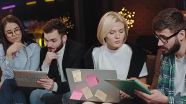 Modern bir kolej kütüphanesinde, çok ırklı öğrencilerden oluşan bir kanepede dizüstü bilgisayar ve elektronik tablet kullanarak bir proje yapmaya başlamayı planlıyorlar.