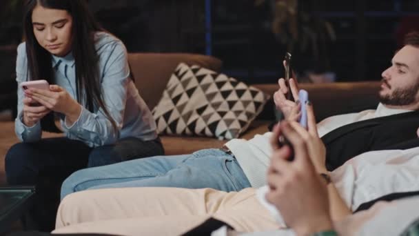 Jongeren studenten zitten op hun smartphone in een universiteitsbibliotheek, terwijl ze lunchen ze socialiseren en zich ontspannen voelen — Stockvideo