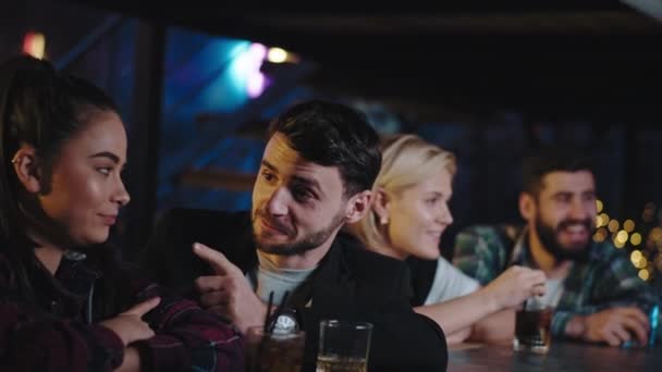 Charyzmatyczne dwie młode pary spędzają razem czas w barze. Każda para rozmawia w dwóch skoncentrowanych i uśmiechniętych osobach. — Wideo stockowe