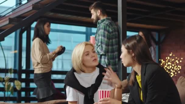 Buen grupo de jóvenes estudiantes en una biblioteca moderna socializando en el sofá otros estudiantes toman fotos y se sienten muy bien — Vídeo de stock