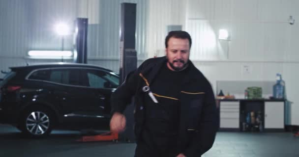 Karismatisk mogen mekaniker efter att han avslutat att fixa bilen dans och flytta roligt framför kameran — Stockvideo