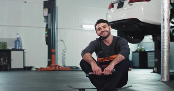 Karismatisk och rolig mekaniker i uniform efter att han avslutat arbetet känns bra och fräsch tittar mot kameran och ler stort. 4k — Stockvideo