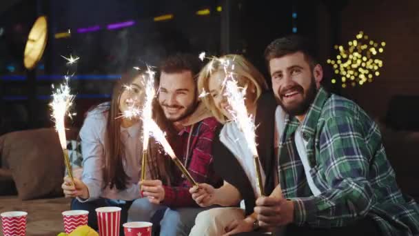 Feliz y sonriente gran hermosa dos parejas jóvenes en casa en la sala de estar mientras se sienta en el sofá tomar algunos destellos y celebrar algún aniversario — Vídeos de Stock