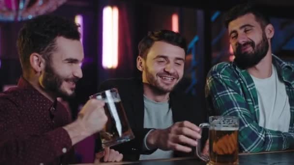 Souriant grands jeunes trois hommes dans un pub boire un peu de bière à partir d'un grand verres ils apprécient l'atmosphère et passer un bon moment. Tourné sur ARRI Alexa Mini — Video