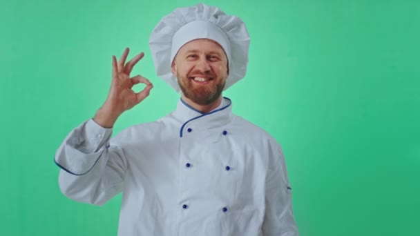 Karismatisk rolig bagare man i uniform inne i en grön studio visar en stor som och ok gestikulera med händerna framför kameran — Stockvideo