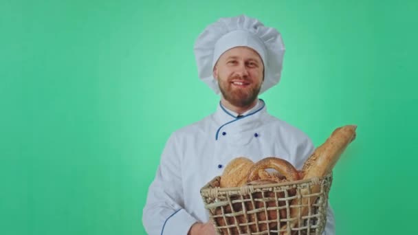 Baker pria yang sangat karismatik tersenyum di depan kamera di dalam studio hijau ia mencium bau roti segar dan merasa bahagia sambil memegang keranjang besar — Stok Video