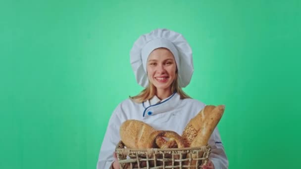 カメラの前に行くために匂いを聞かせするために手でジェスチャー新鮮なパンのバスケットを保持大規模な笑顔で良い見て女性のパン屋 — ストック動画