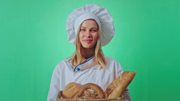 Vor der Kamera eine schöne Dame mit blondem Haar Bäckerin hält einen großen Korb mit frischem Brot sie riecht das Brot in einem Chroma-Schlüssel — Stockvideo