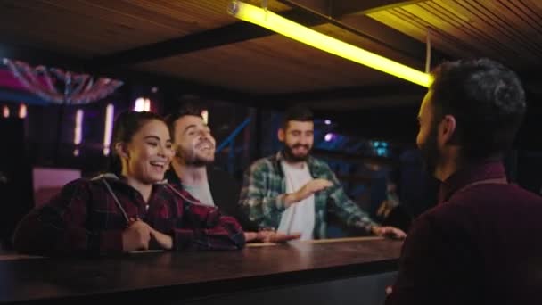 Em um bar moderno, jovens excitantes e diversificados começam a apertar as mãos na mesa de bar enquanto esperam por seus coquetéis — Vídeo de Stock