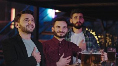 Bar masasında bira içerken gülen ve eğlenen bir grup karizmatik arkadaştan oluşan bir spor barında kendilerini çok rahat hissediyorlar.