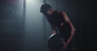 Jimnastik sınıfı konsepti güçlü atletik adam, çapraz formda bir top ile kameranın önünde sıkı antrenman yapıyor ve terliyor.