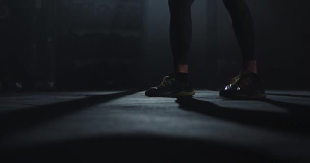 Λεπτομέρειες ενός αθλητή που χρησιμοποιεί μια μπάλα cross fit για να κάνει ασκήσεις προπόνησης σε ένα σκοτεινό μάθημα γυμναστικής — Αρχείο Βίντεο