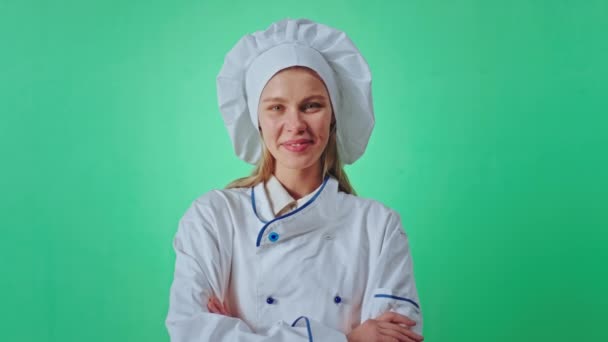 Красивая девушка пекарь позирует перед камерой внутри зеленой студии хрома ключ она улыбается красиво и скрещивая руки — стоковое видео