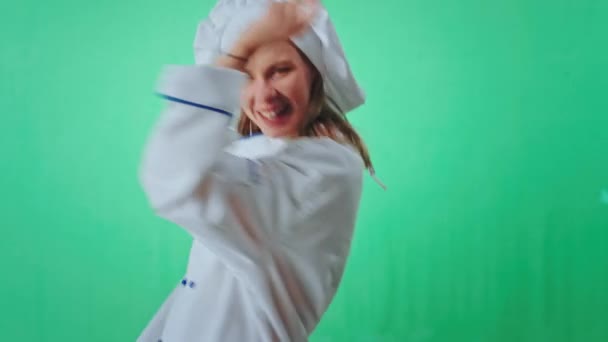 Зеленая студия красивая блондинка пекарь танцует и улыбается, глядя прямо в камеру, она очень взволнована — стоковое видео