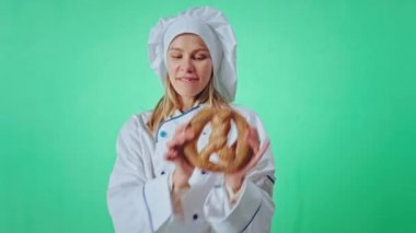 Büyük gülümseyen fırıncı kadın kameranın önünde Fransız krakeriyle dans ederken yeşil, büyük bir stüdyo arka planında komik bir yüz ifadesi takınıyor. Arri Alexa Mini 'ye ateş edildi.