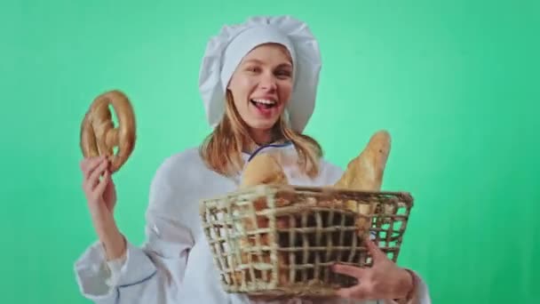 Opgewonden bakker vrouw met een grote mand van een vers brood dansen voor de camera ze kijkt naar de camera maken grappige gezicht chroma key studio — Stockvideo