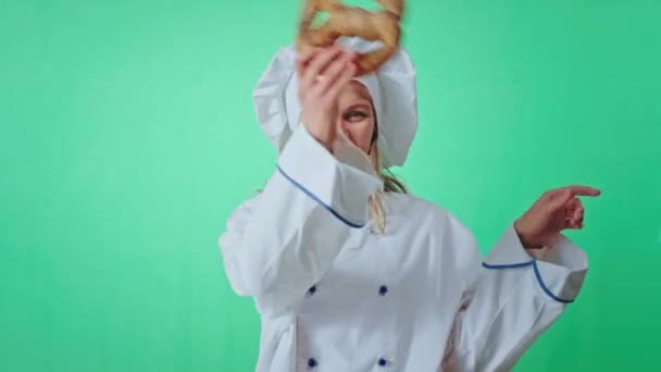 Happy baker vrouw in een groene studio spelen en dansen met een frisse pretzel ze mooi gezicht kijken recht naar de camera chroma key concept — Stockvideo