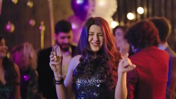 Beautiful and stylish lady in a sparkling dress enjoying the time at glamorous party dancing and smiling large while holding a glass of sparkling wine — Wideo stockowe