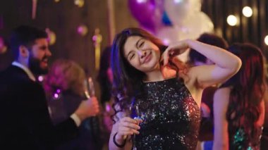 In front of the camera smiling and feeling happy beautiful lady enjoying the time she dancing at glamorous party background other people enjoying the evening