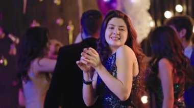 Big party in front of the camera attractive lady holding a glass of champagne and dancing smiling and feeling relaxed. Shot on ARRI Alexa Mini